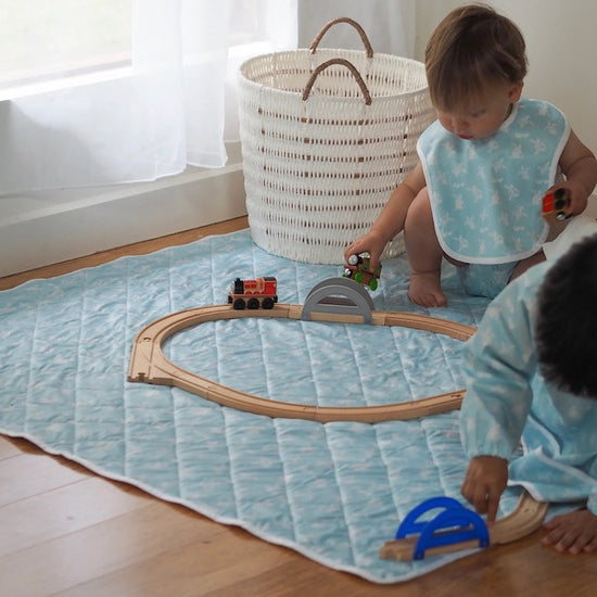 Two children playing on a turquoise play mat