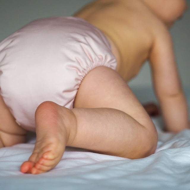 Baby wearing a blush pink cloth nappy