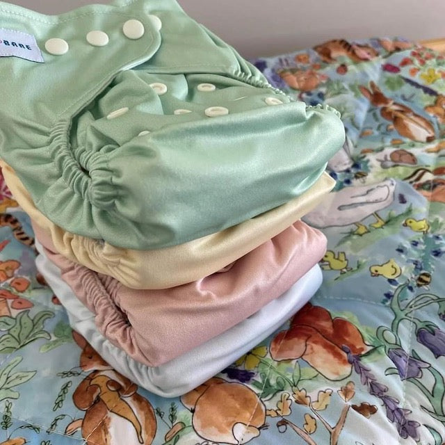 Stack of plain colour cloth nappies on a Baby Bare playmat