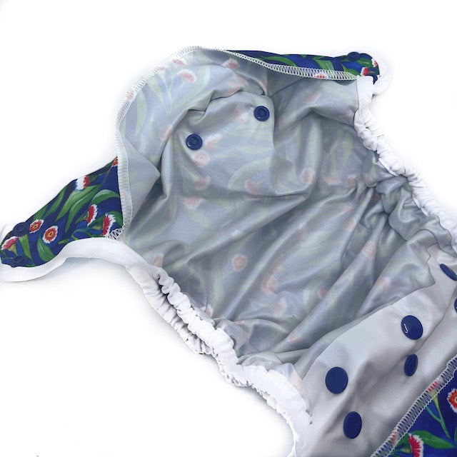 The inside of a Baby Bare nappy wrap cover featuring navy blue snap closures