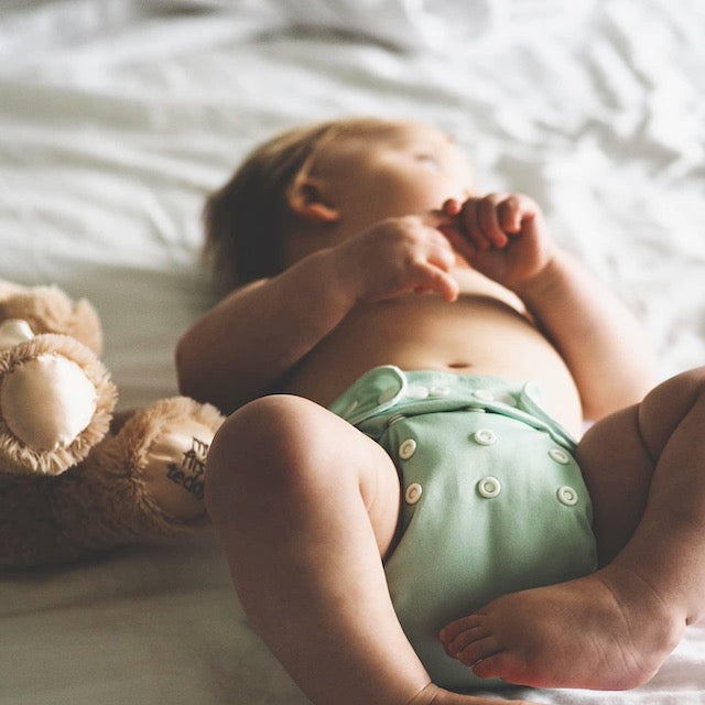 Baby wearing a mint green cloth nappy