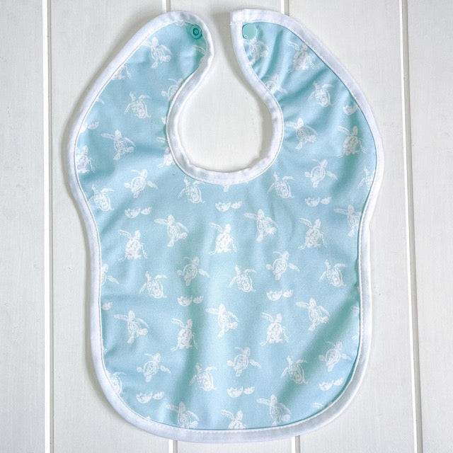 A blue baby bib featuring a turtles print