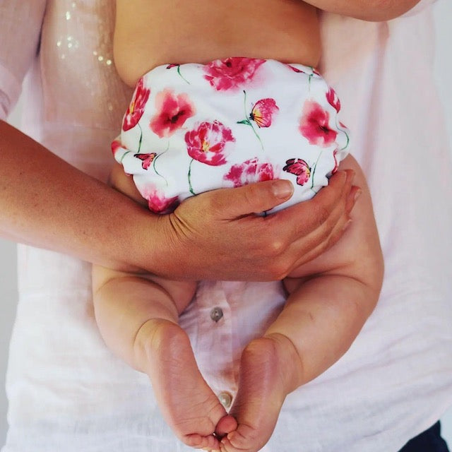 Parent holding a baby wearing a white and pink nappy featuring buttflies