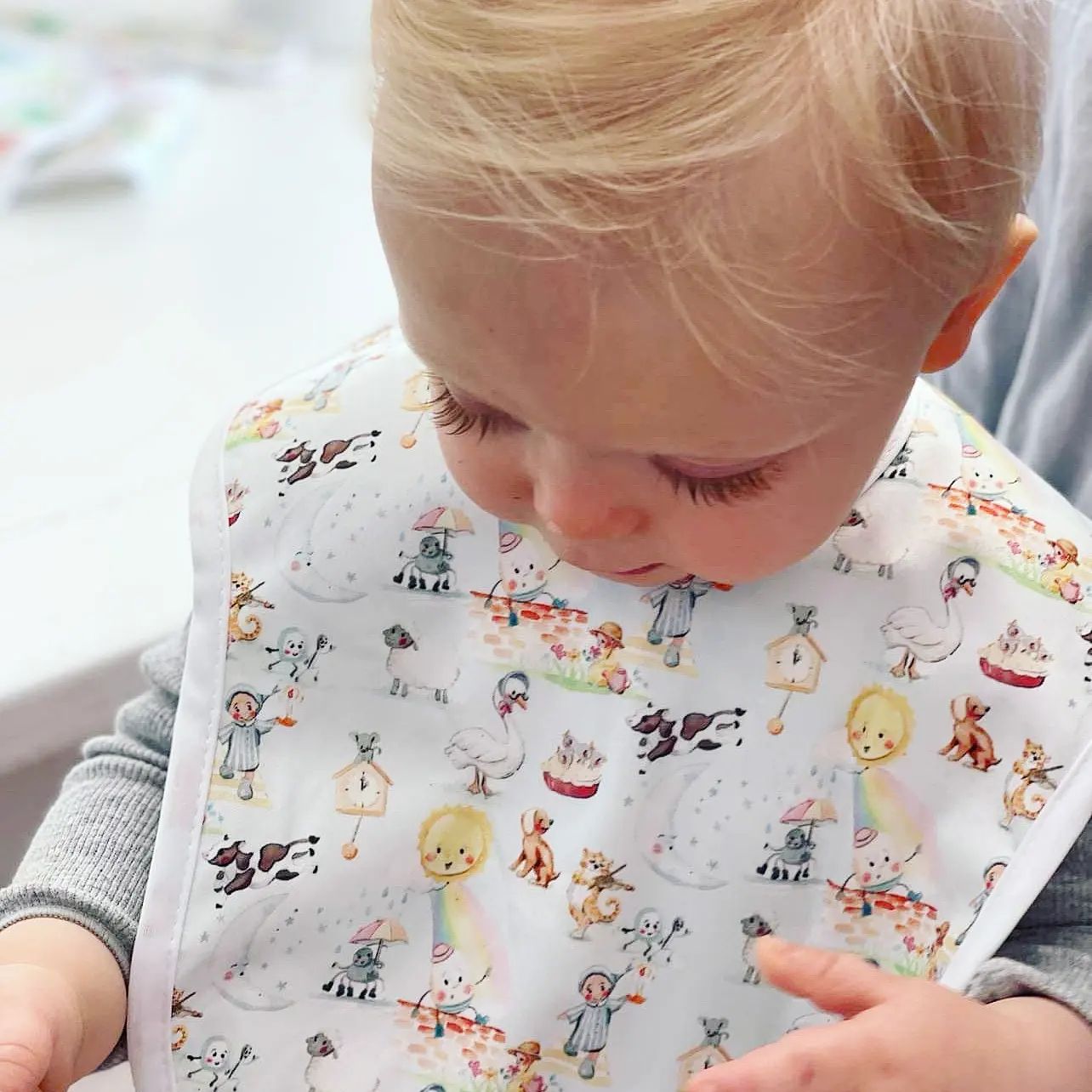 Baby wearing a bib featuring a nursery rhyme print