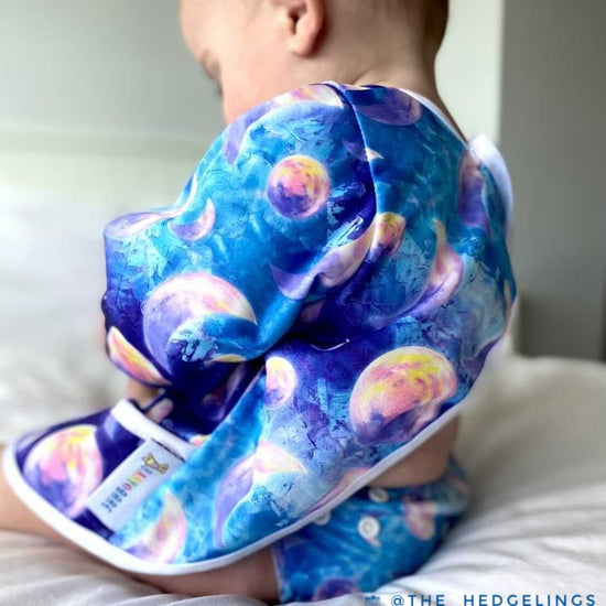 Baby wearing a blue Baby Bare smock featuring a moon print