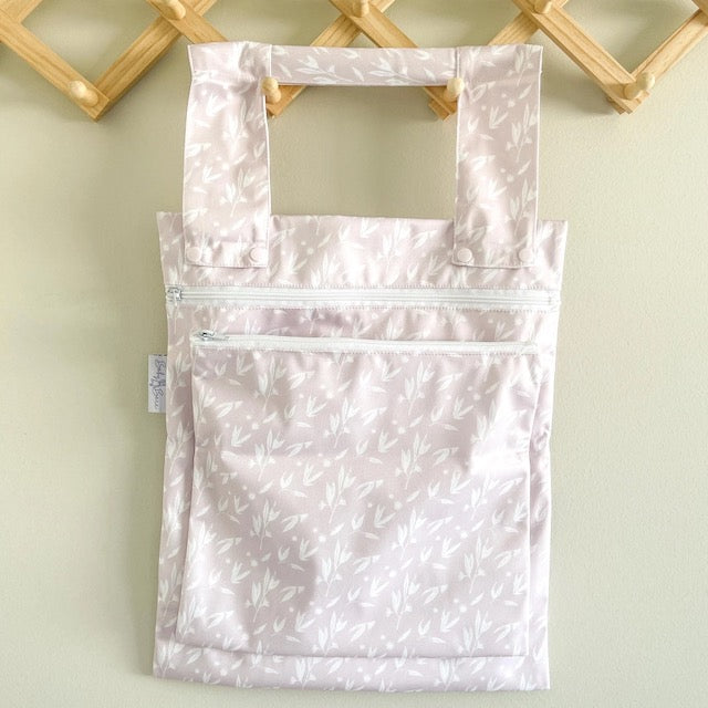 A pink double wet bag with a blossom design on a hanger