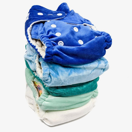 A stack of blue, green and white cloth night nappies