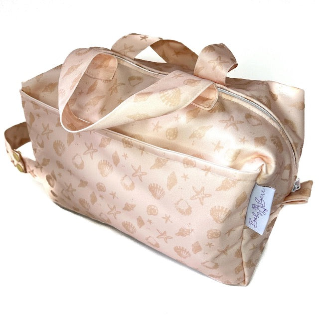 A pink pod style wet bag with a sea shell design