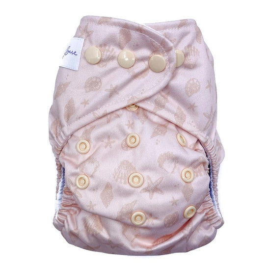 A reusable cloth nappy with a sea shells print on a pink base